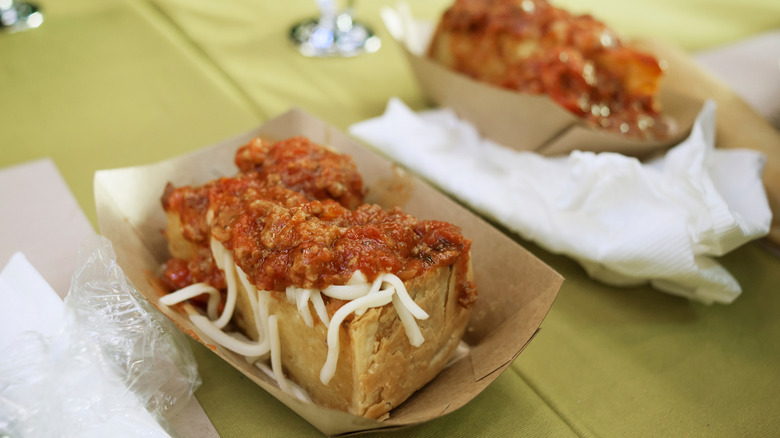 Two servings of Olive Garden's Deep Dish Meatball Spaghetti Pie, resting in cardboard containers