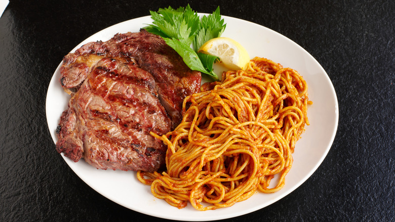 A plate of grilled steaks and spaghetti