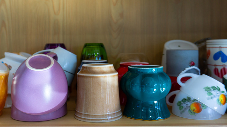 Multiple mugs stacked in cabinet
