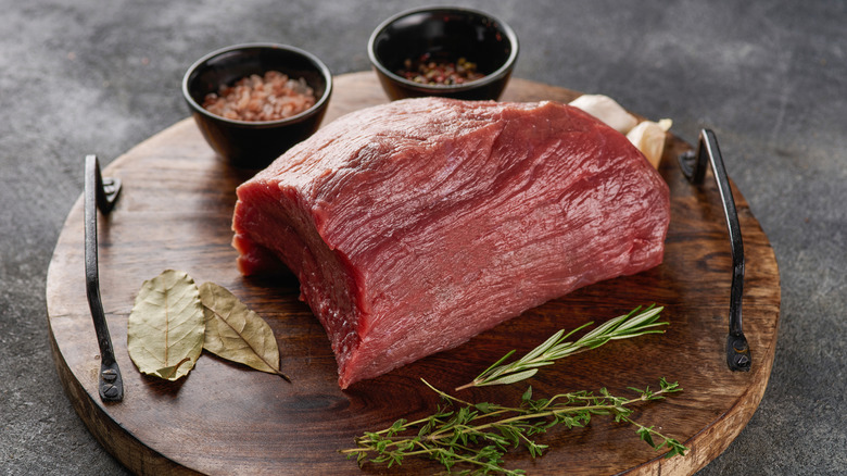 A raw rump steak alongside spices
