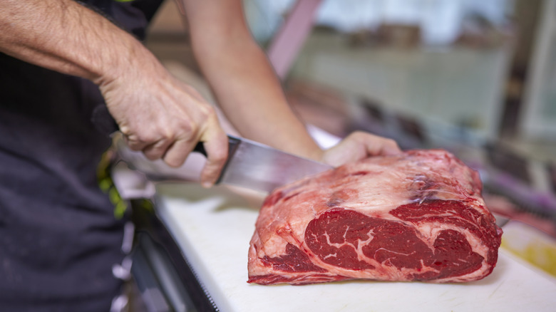 A butcher cutting a raw sirloin steak