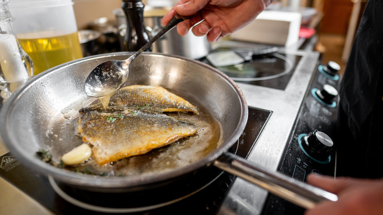 Fish cooking in a stainless steel pan