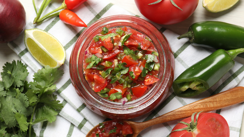 Salsa in a glass bowl surrounded by veggies