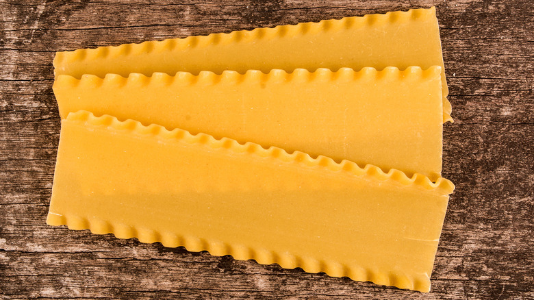 Uncooked lasagna sheets on wood board