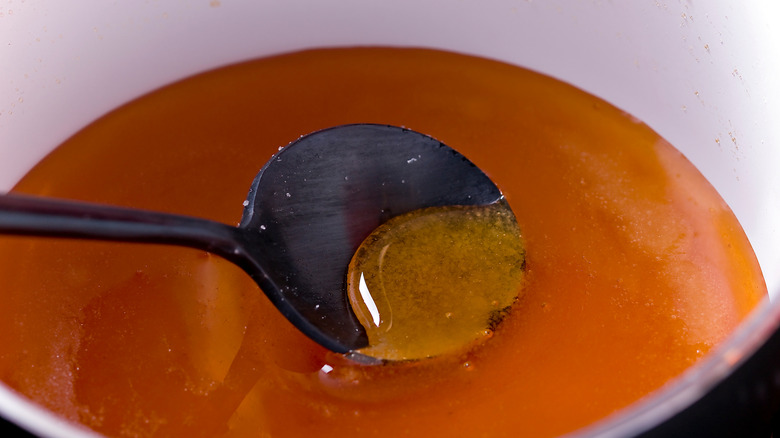 Caramel syrup inside pot with white interior with black spoon