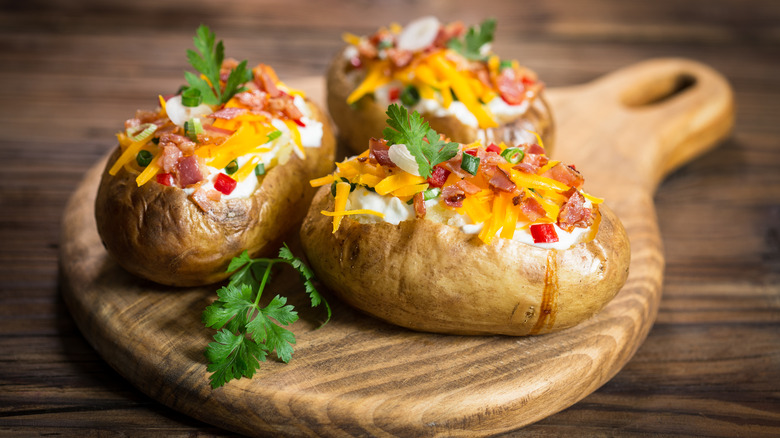 Three baked potatoes with toppings.
