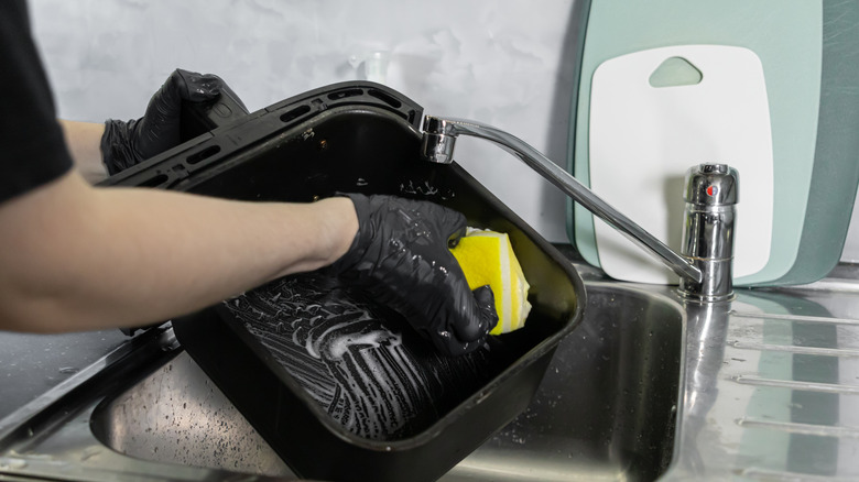 Someone cleaning an air fryer with a sponge