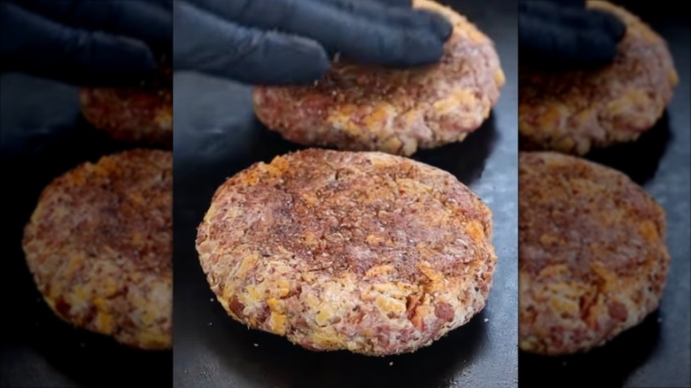 Burger with two smashed patties, bacon, and cheese next to pile of french fries
