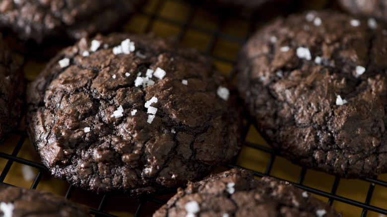 A tray of fudgy, sea-salt topped chocolate cookies cooling on a rack