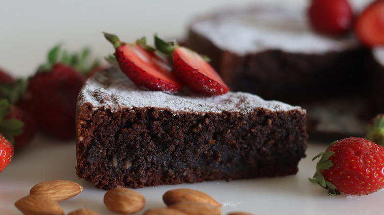 A slice of flourless chocolate torte with strawberries and almonds