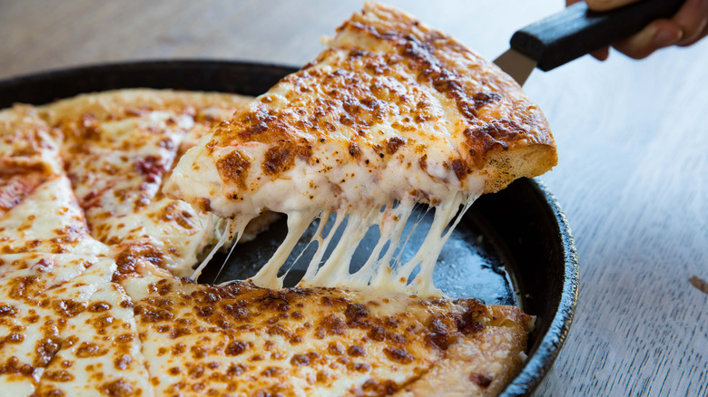 A cheesy pizza from Pizza Hut being sliced