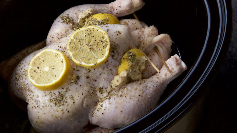 Whole chicken with herbs and lemons in slow cooker