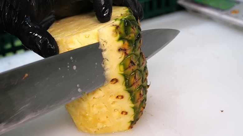 Person cutting a pineapple
