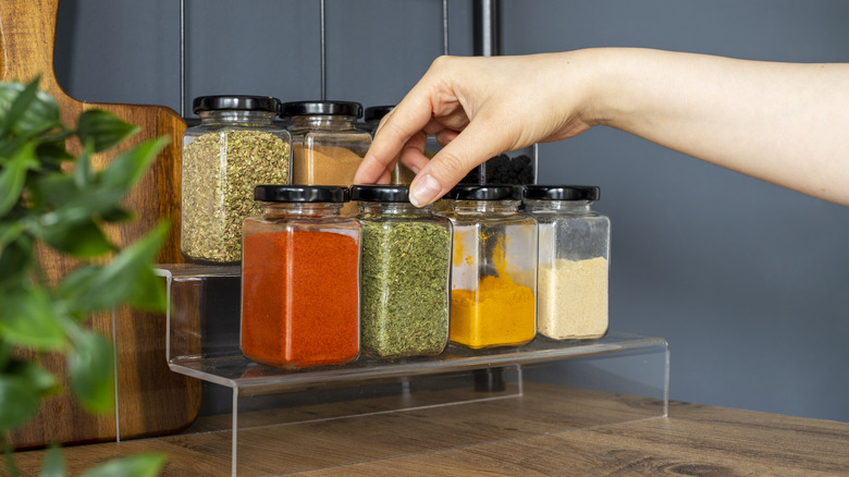 Hand picking spice jar from shelves on counter