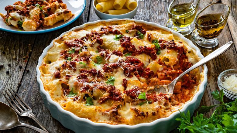 A large dish of cheesy rigatoni with sausage on a wooden table