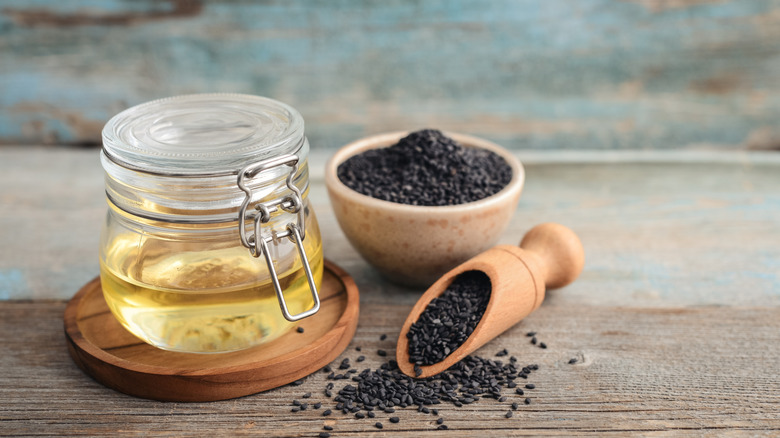 Black sesame seeds in bowl and jar of oil