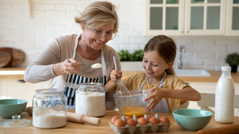 grandmother and granddaughter mixing ingredients.
