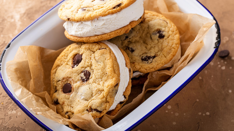 chocolate chip cookie ice cream sandwiches in a blue and white dish lined with parchment paper on a brown countertop