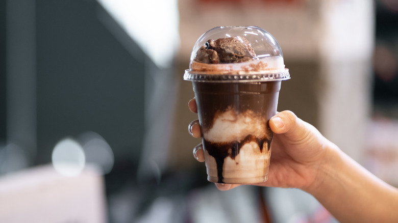 Someone holds up a makeshift affogato in a plastic cup
