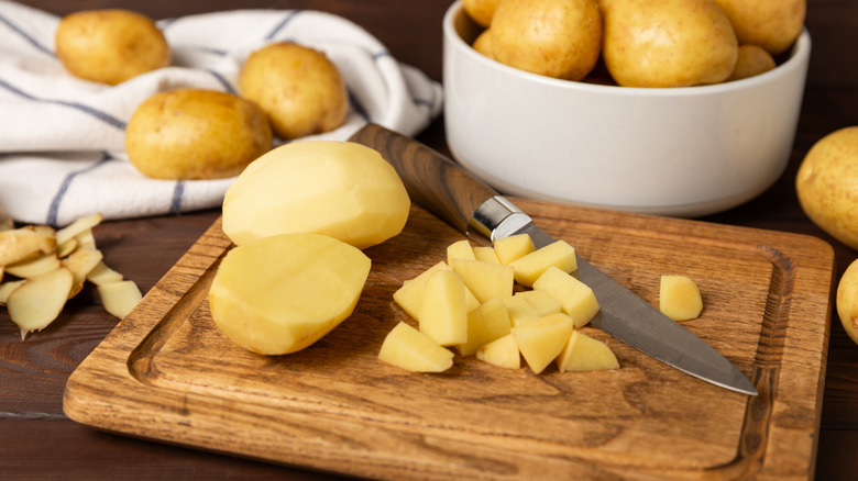 Peeled and chopped potatoes on cutting board beside knife