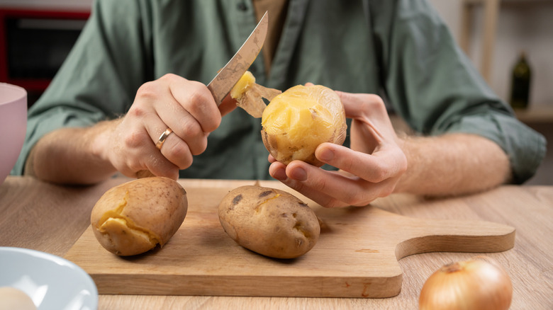 Person peeling potatoes with a knife