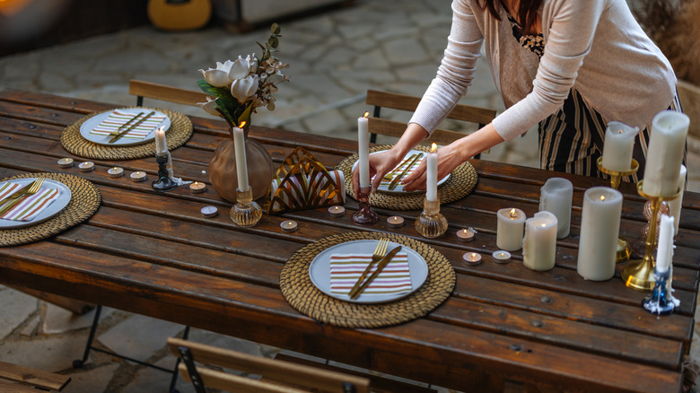 Woman setting table outdoors.