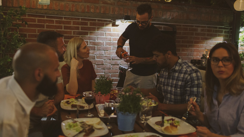 A server pours wine for a group seated at a restaurant table