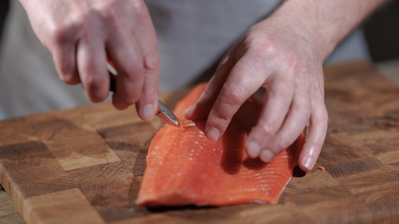 male hands removing pin bones from salmon with pliers