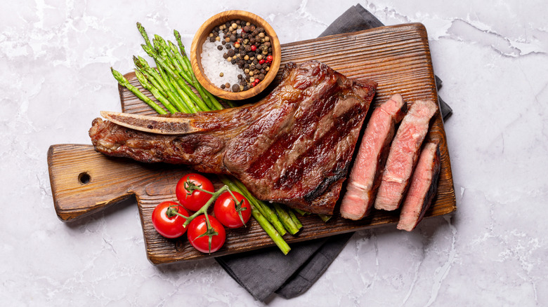 bone-in steak cooked to medium and sliced on a wooden board