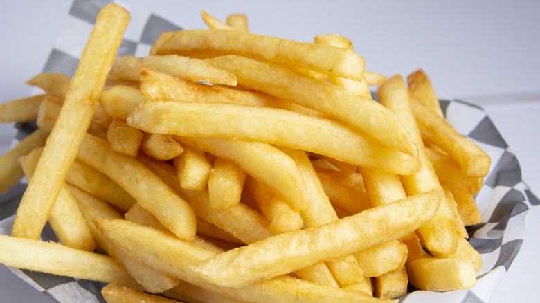 A serving of fast food French fries in a white paper takeout box