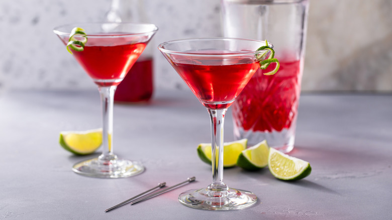 Two cranberry martinis with shaker and limes