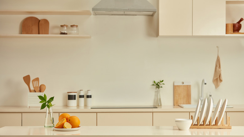 Kitchen counter with utensil crock, oranges on plate, plates on wooden rack