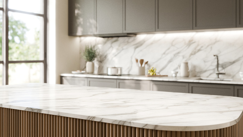 Clean white marble kitchen island, blurred tidy kitchen counter behind