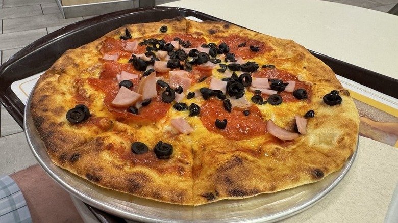 McDonald's pizza with tomatoes, onions, and black olives as toppings.