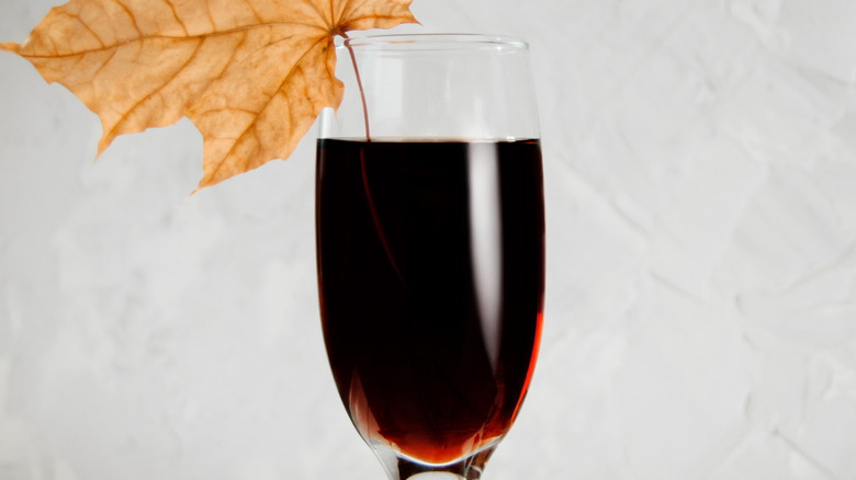 A chilled red wine cocktail is garnished with a fall leaf in the glass.