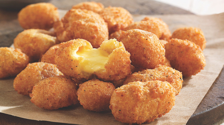 Closeup of fried cheese curds with one split open to show melted cheese inside