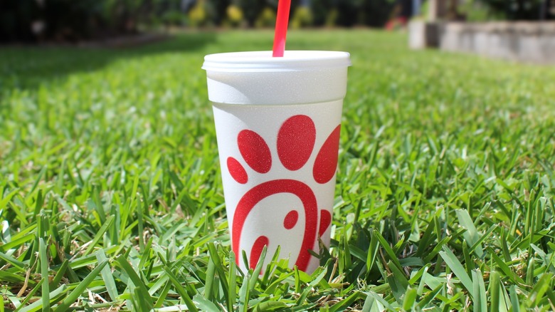 A Chick-fil-A cup and straw on a grassy lawn