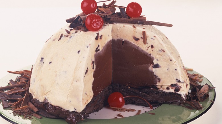 A cream and brown colored ice cream bombe dessert topped with cherries