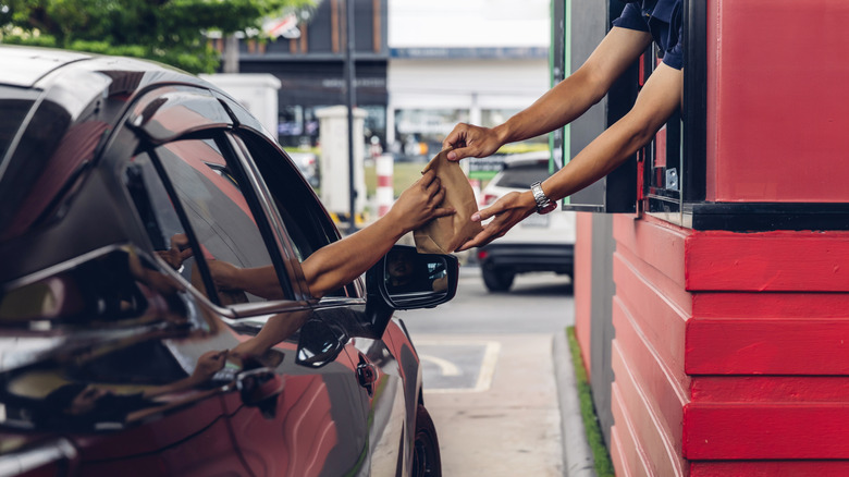 Fast food worker hands out food at drive thru