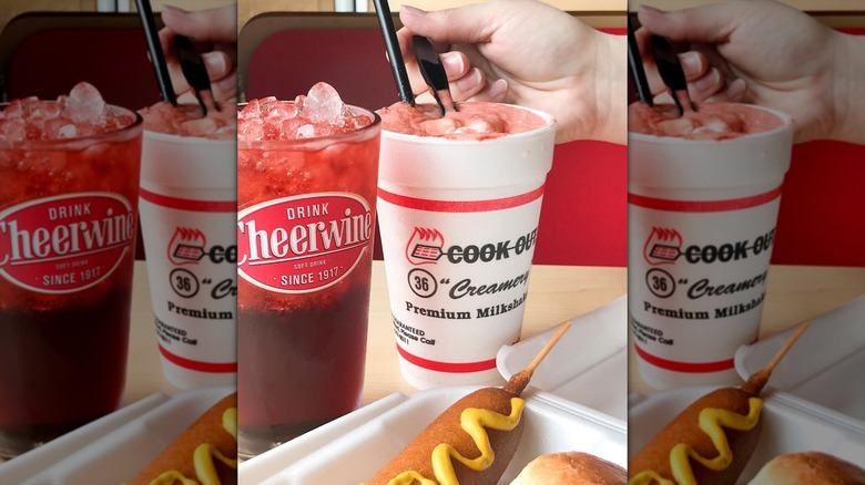 A pink Cook Out milkshake in a foam cup with a spoon and straw