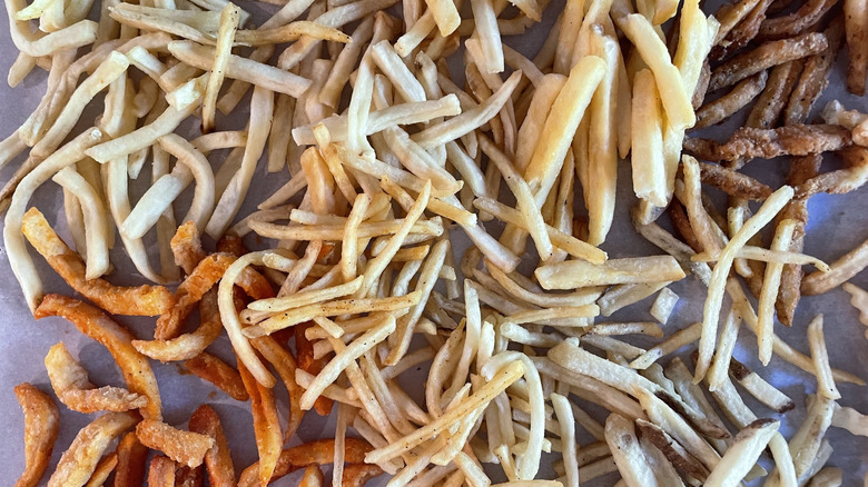 Collection of fast food fries laid out on a table on parchment paper