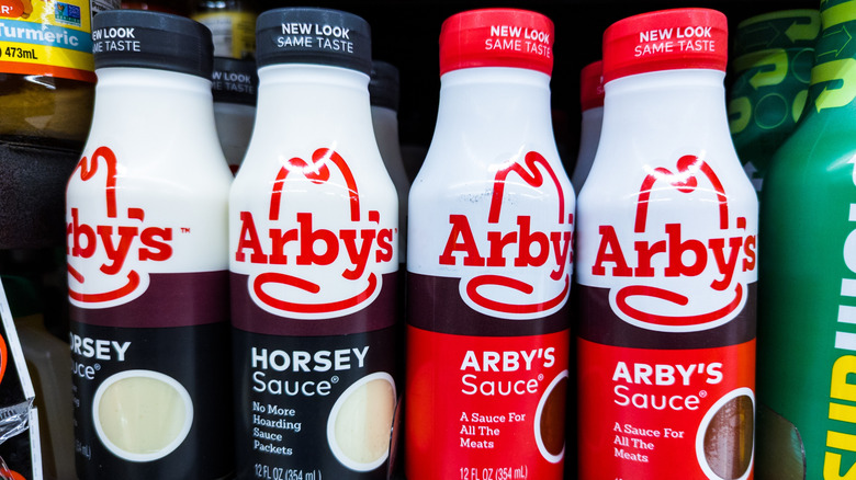A grocery store display of bottles of Arby's Sauce and Horsey Sauce