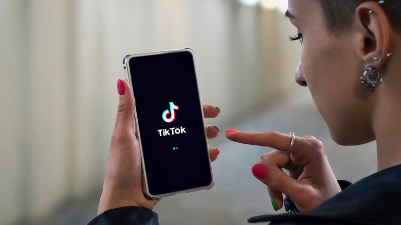 A person opening the TikTok app on a smartphone