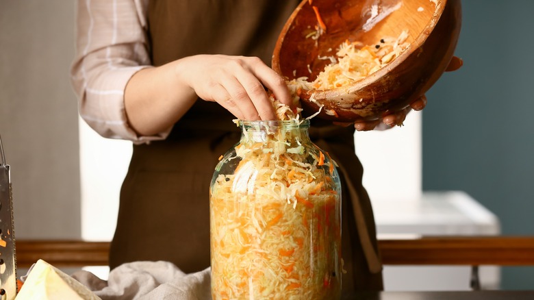 Women putting fermented food in jar