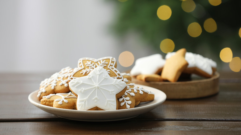 Decorated cookies on wooden against blurred Christmas lights