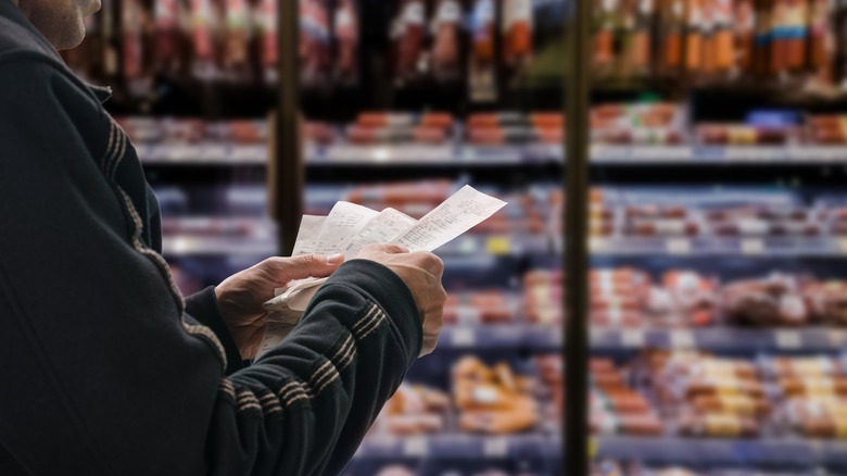 Person looks receipts in grocery aisle