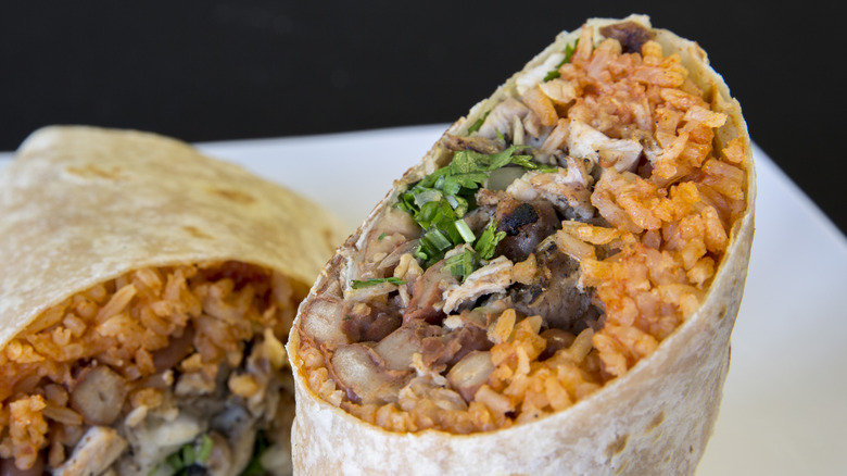Close up on a burrito filled with chicken, beans, cilantro, and a lot of rice