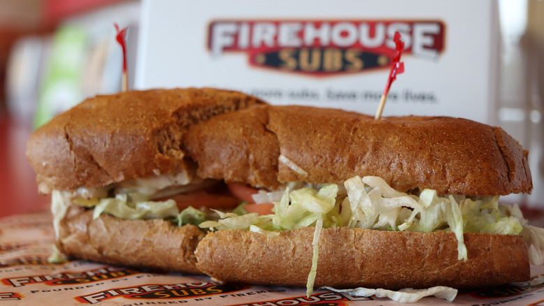 A Firehouse Sub sign behind a sandwich with toothpicks