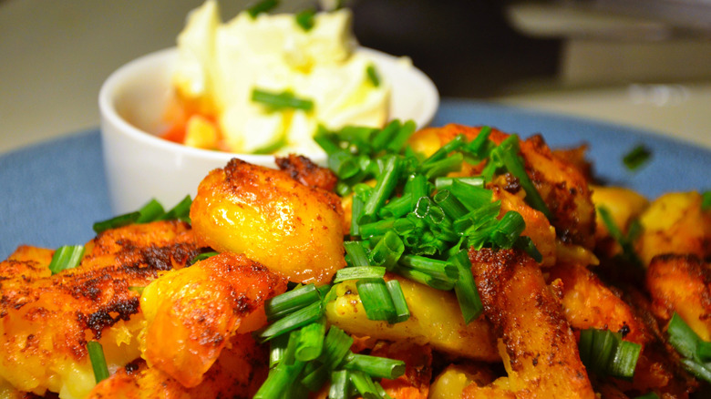 A plate of roasted potatoes garnished with freshly chopped chives