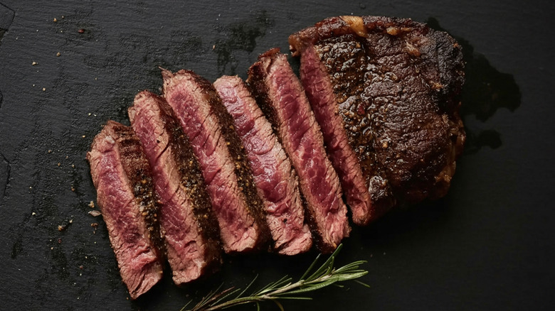 Sliced-up ribeye on dark background.